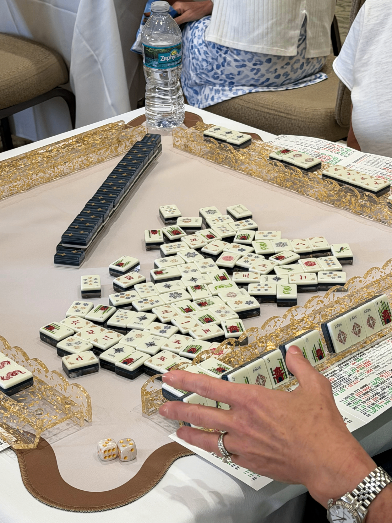 Mahjong tiles mid-game on a lace-trimmed table