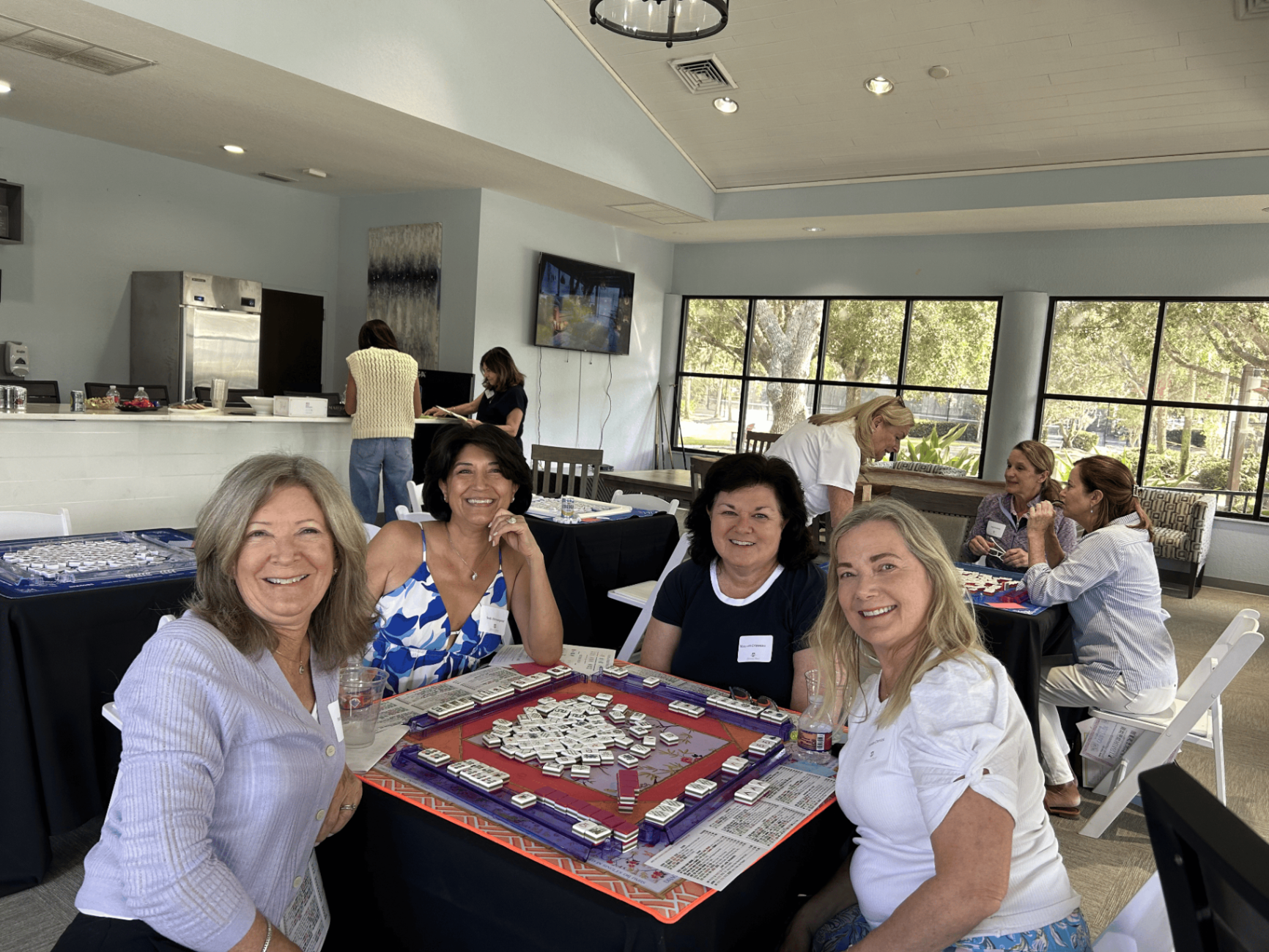 Four friends smiling around a mahjong table